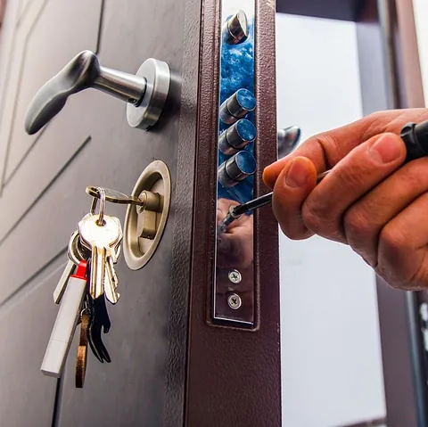 manos de cerrajero profesional colocan cerradura en canto de puerta